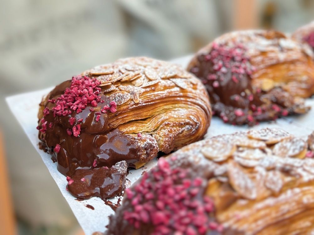 A close up of three pastries with chocolate and powdered sugar on a table.