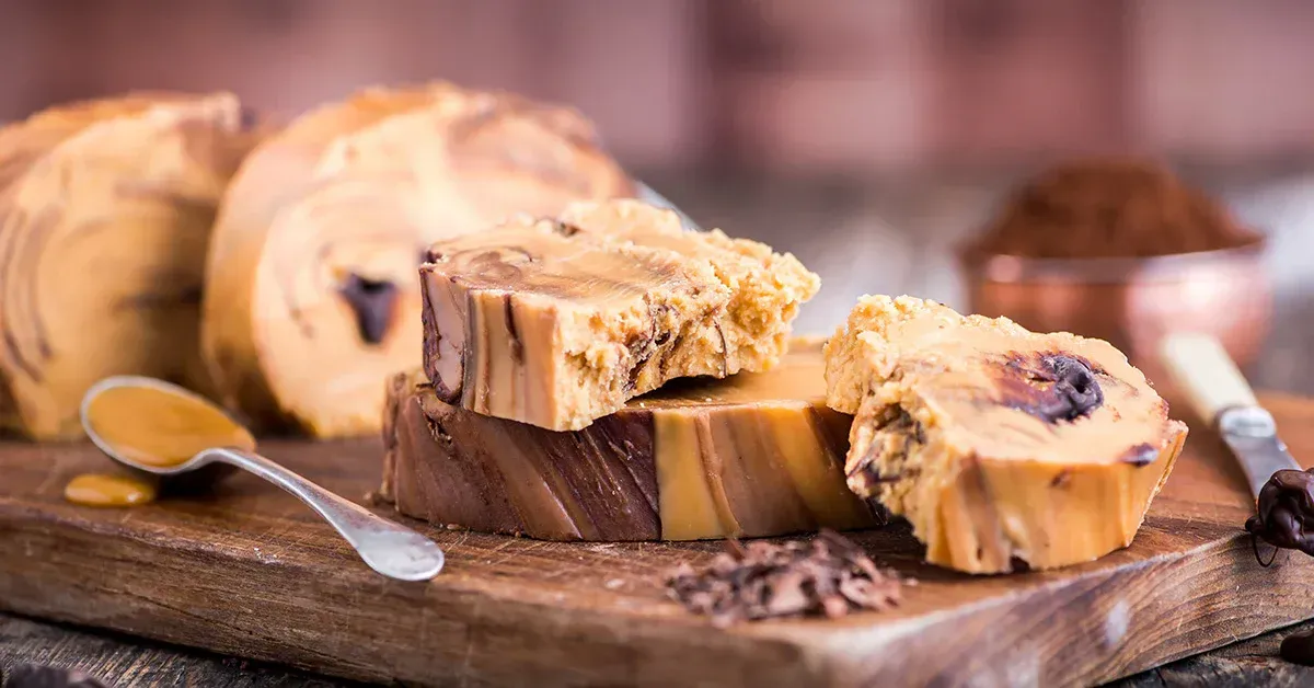 A piece of fudge is sitting on top of a wooden cutting board.