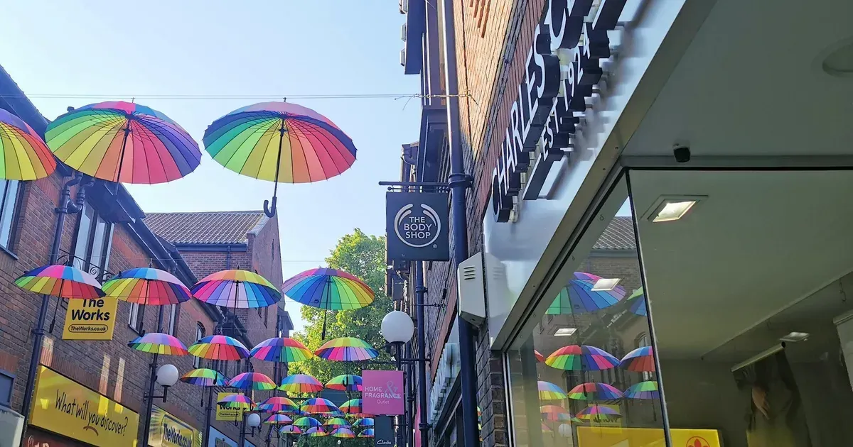 Rainbow umbrellas strung above a shopping street.