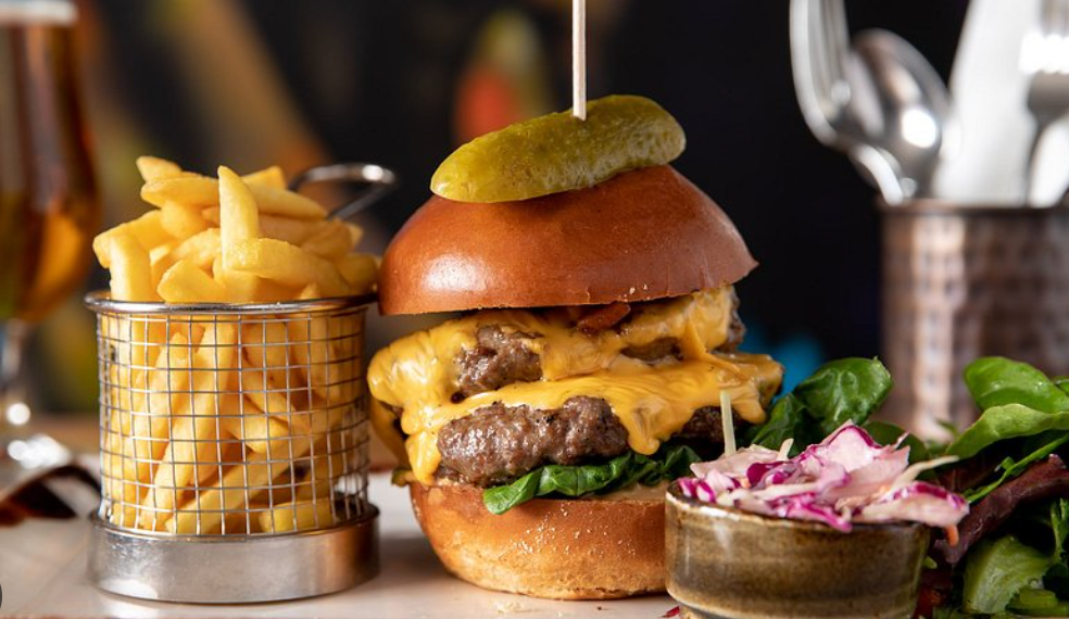 A close up of a hamburger and french fries on a table.