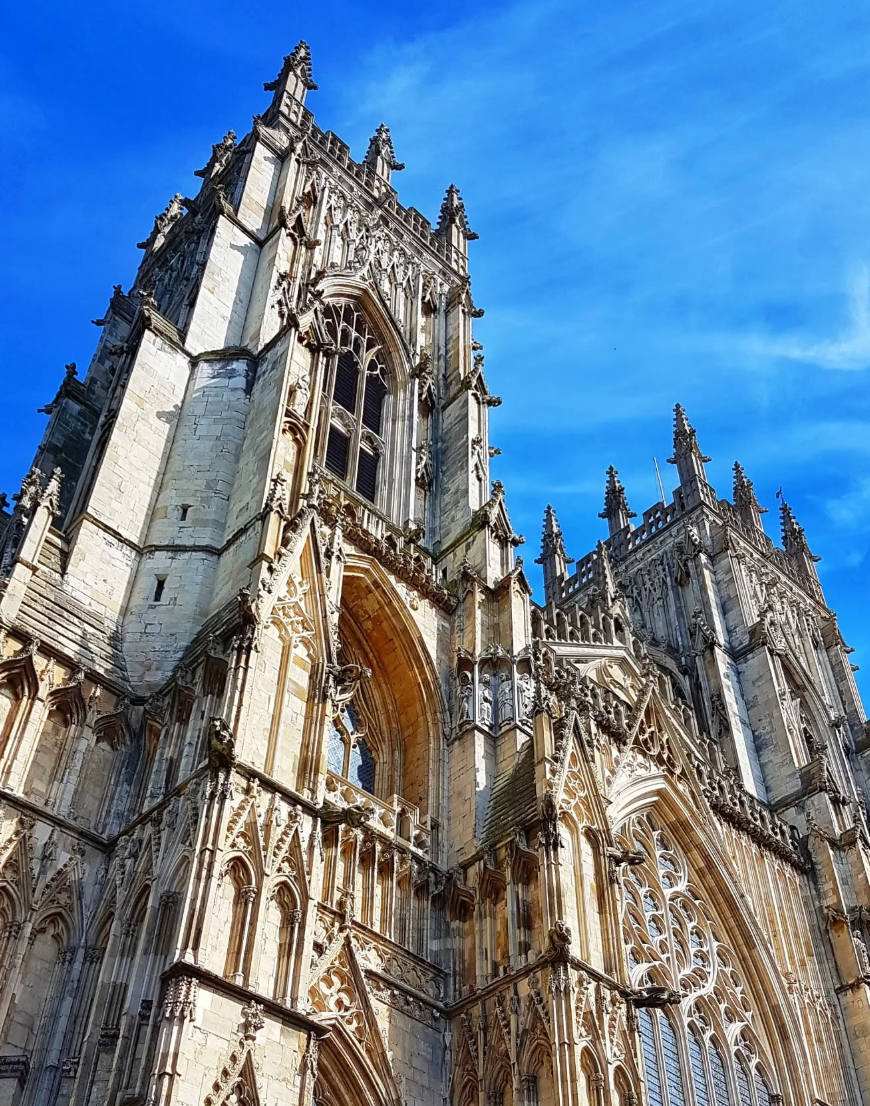 Gothic cathedral, tall and ornate, against a bright blue sky.