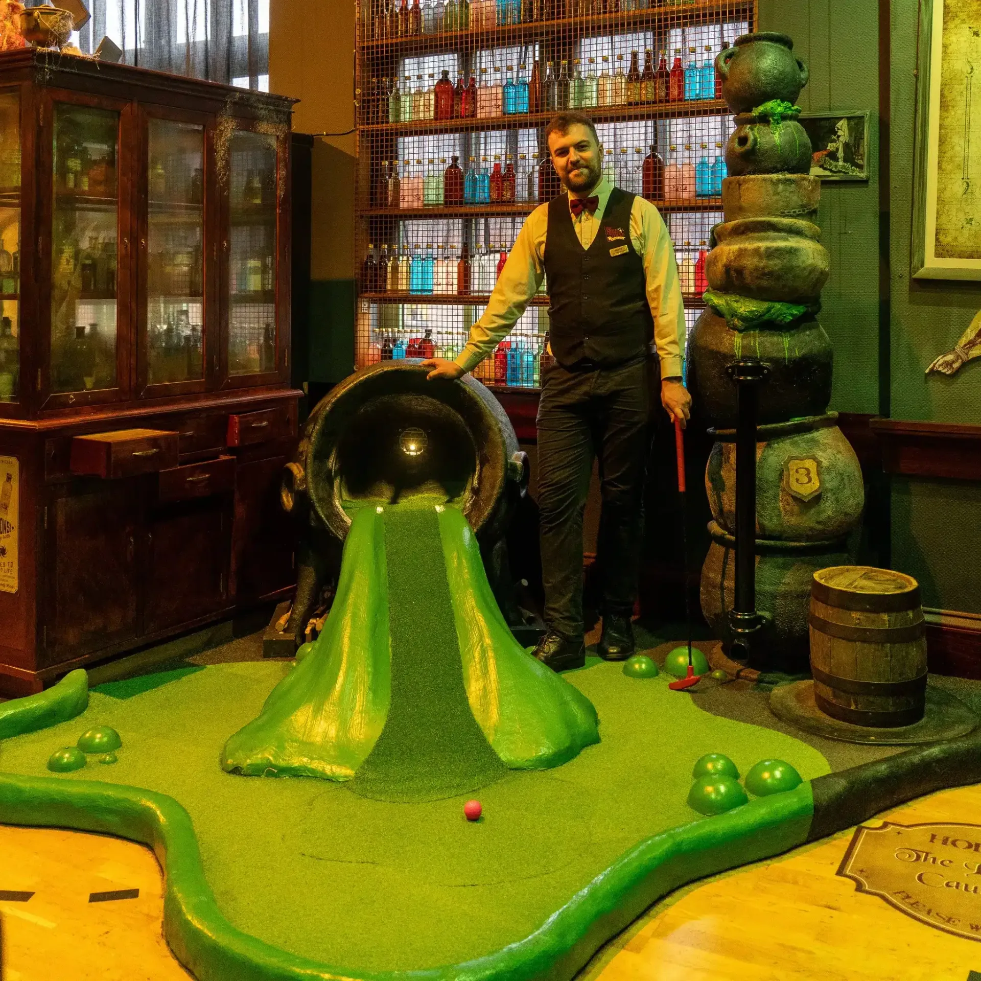 Man at a themed indoor mini-golf course. Green 