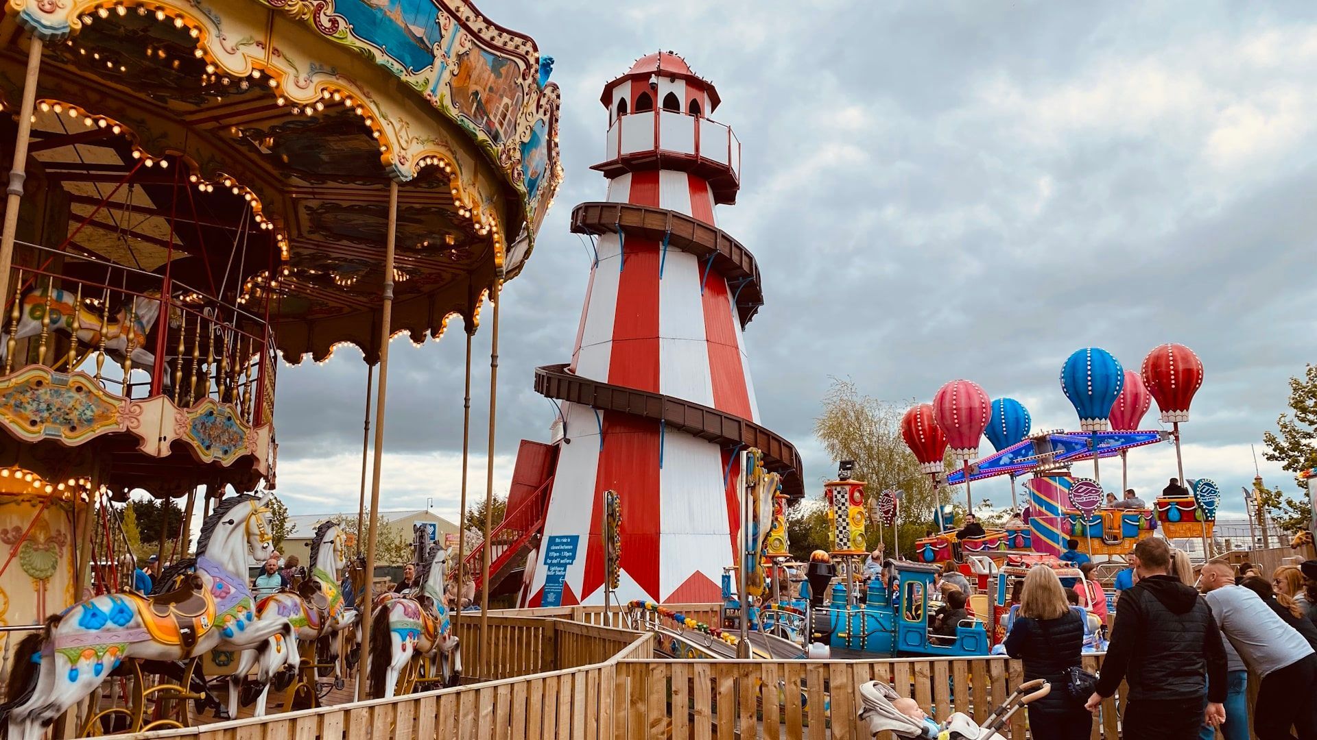 A carousel and a lighthouse are at an amusement park.