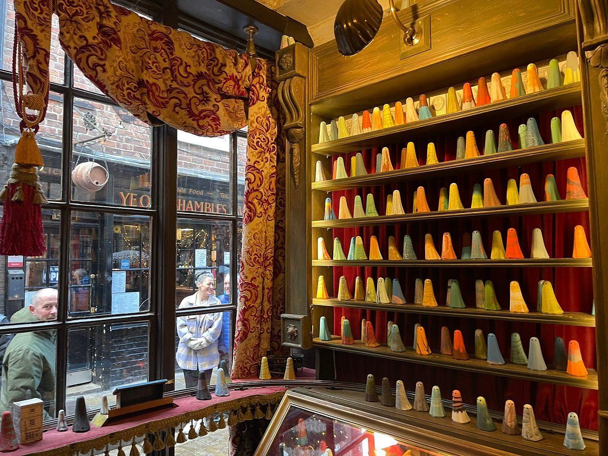 A shop window displays rows of colorful, cone-shaped candies. People look in from outside.