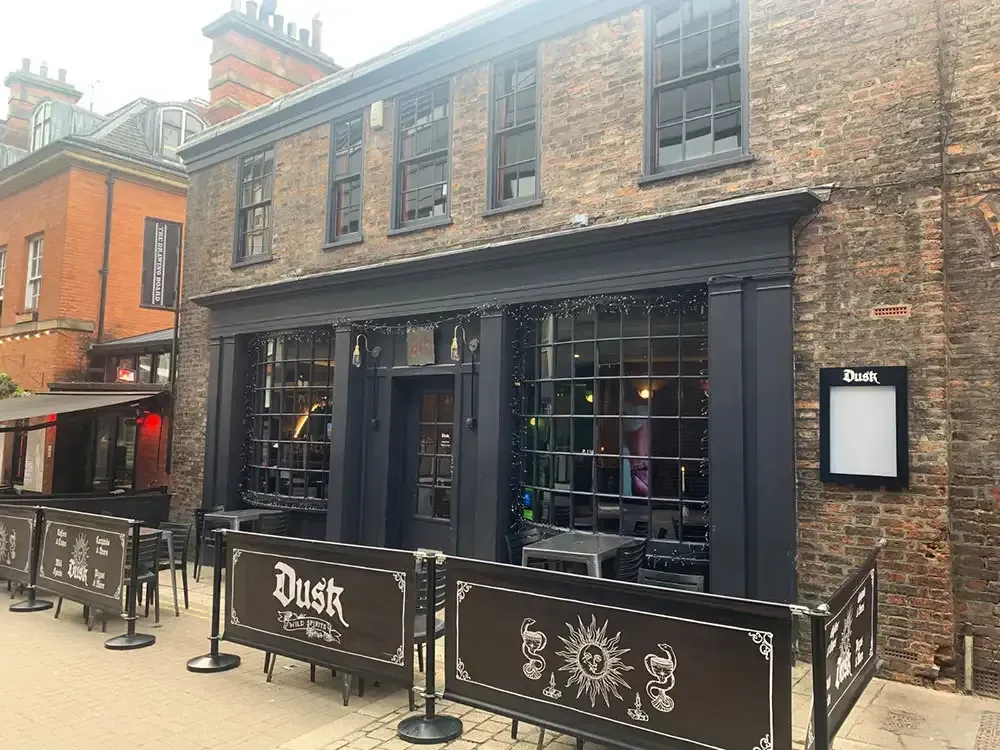 Dusk restaurant exterior, brick building with black trim and outdoor seating, York, England.