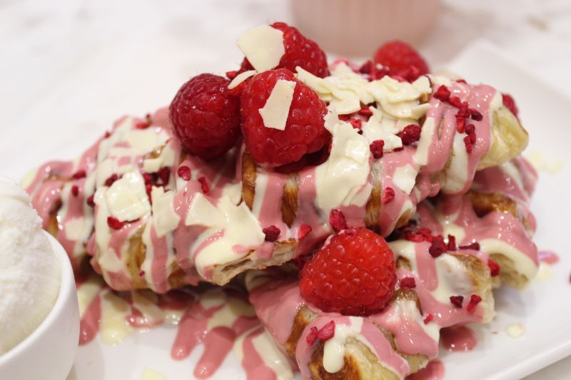 A close up of a plate of food with raspberries and white chocolate.