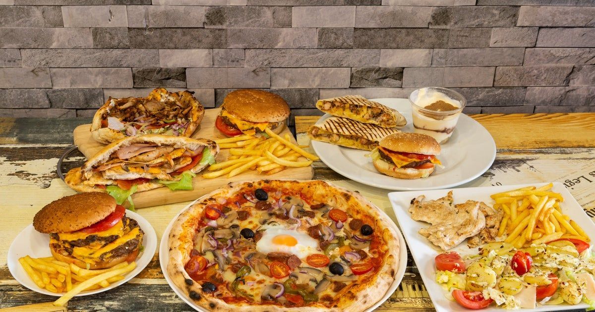 Assortment of fast food dishes: pizza, burgers, fries, sandwiches, and a dessert.
