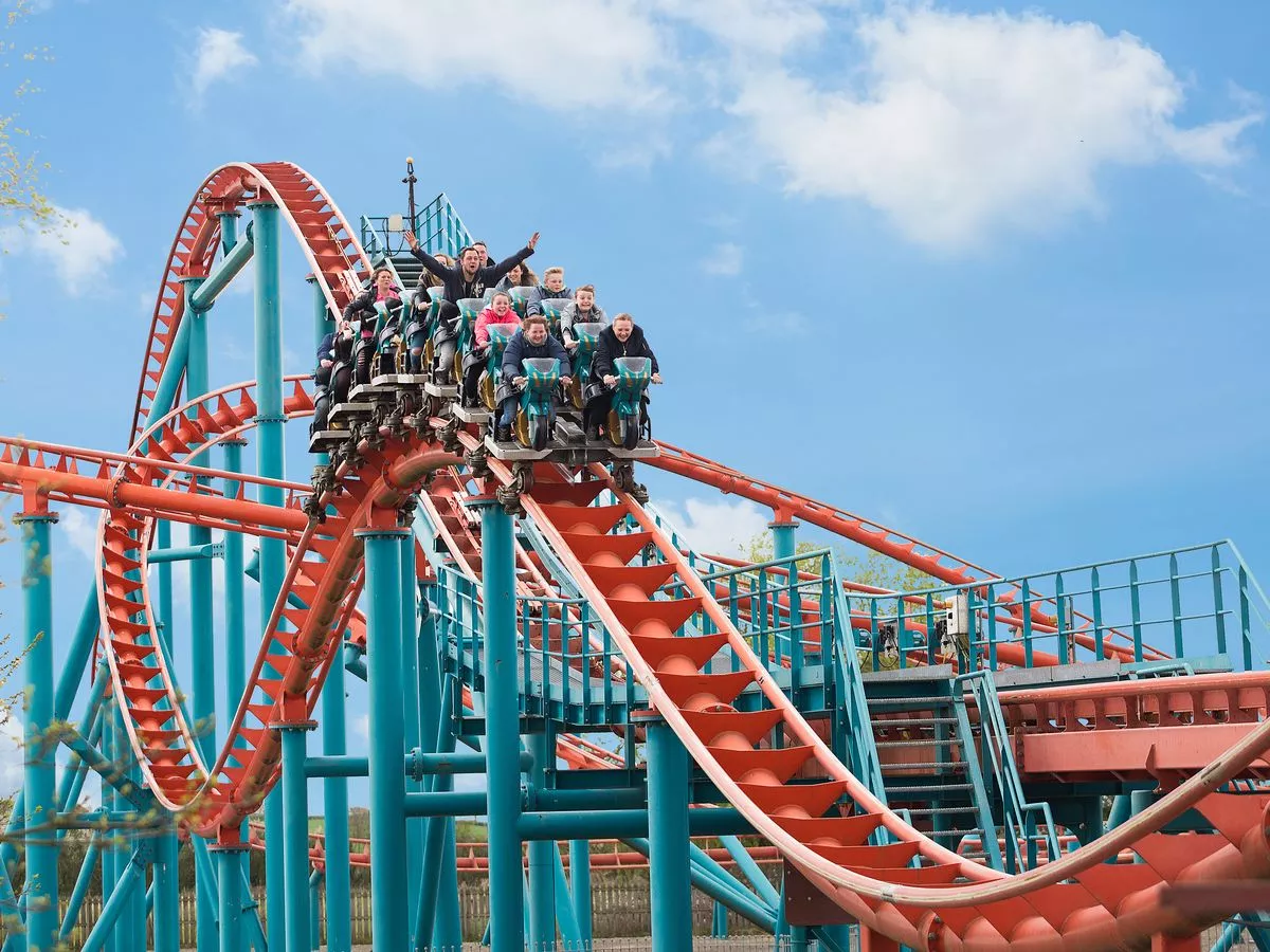 A group of people are riding a roller coaster at an amusement park.