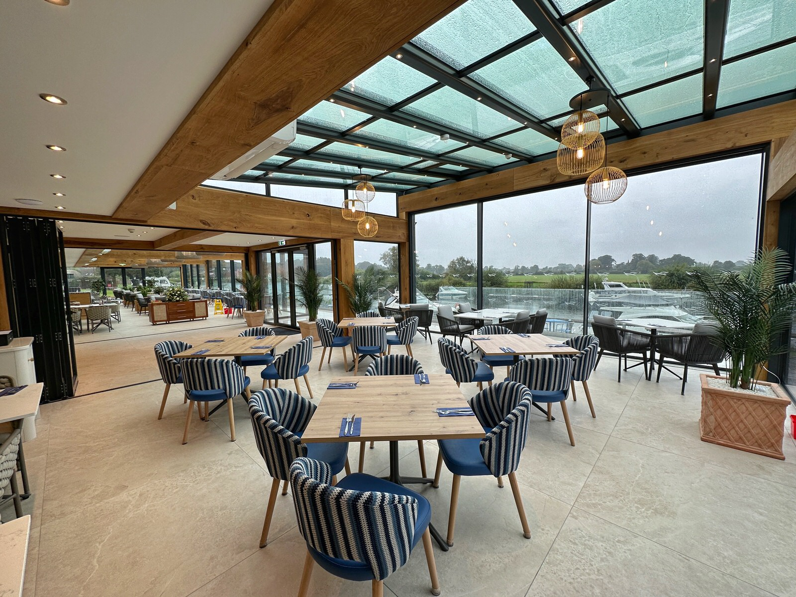 A restaurant with tables and chairs and a glass roof.