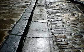 Cobblestone street with a channel, wet and reflecting light.