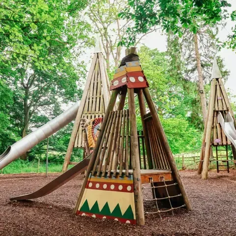 A playground with a slide and a teepee in the shape of a teepee.