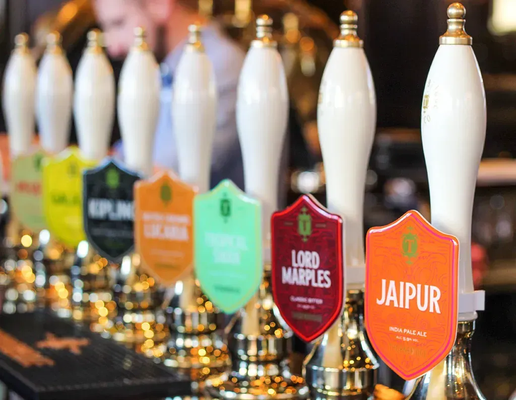 Row of beer taps with colorful labels at a bar, including 