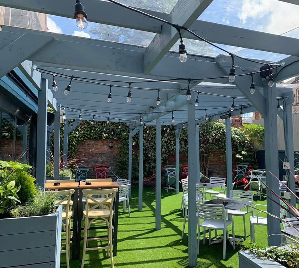 Outdoor dining area with string lights, tables, and artificial grass.