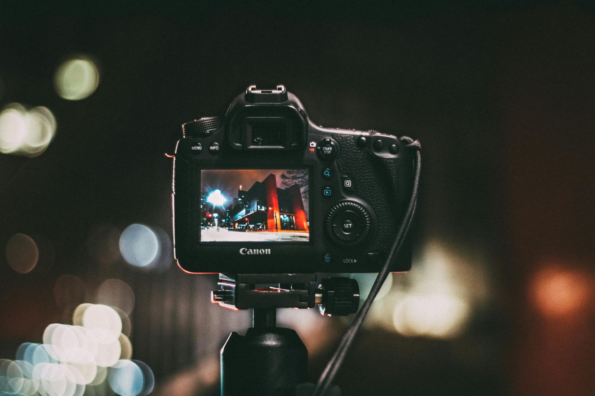 Camera on tripod capturing nighttime scene with lights.