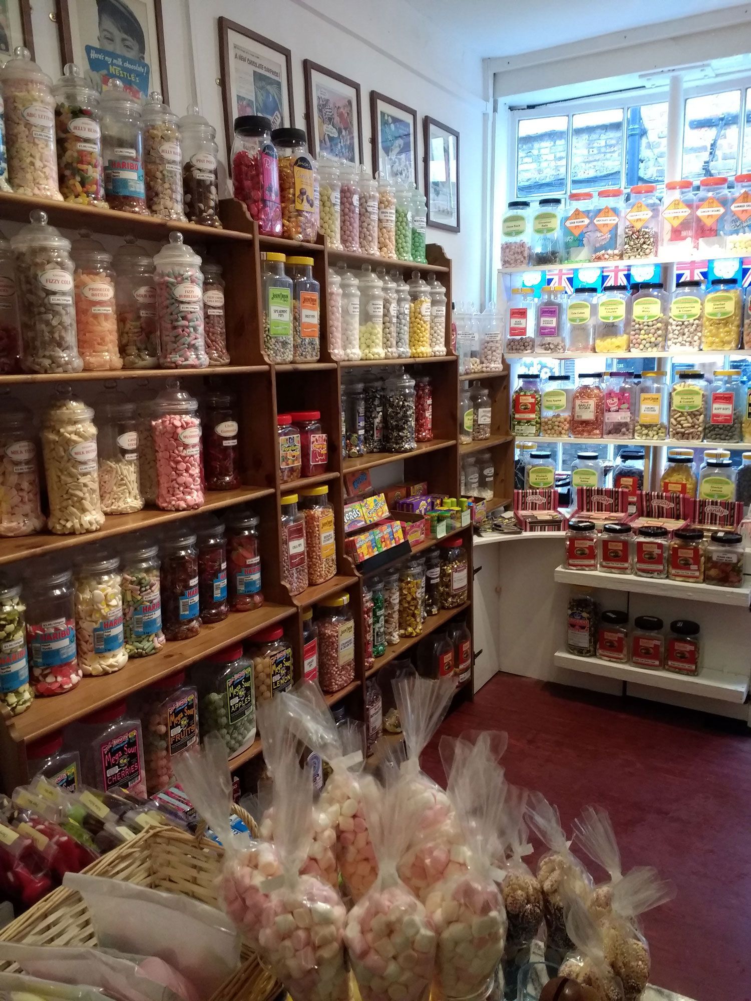 A candy shop with shelves filled with jars of sweets. Foreground has bags of marshmallows.