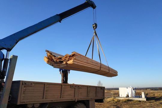Una grúa está levantando un gran trozo de madera de un camión.