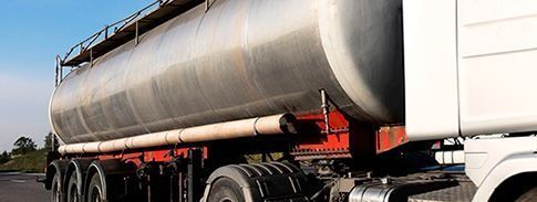 Gran remolque cisterna plateado en una carretera, visto de lado a plena luz del día.