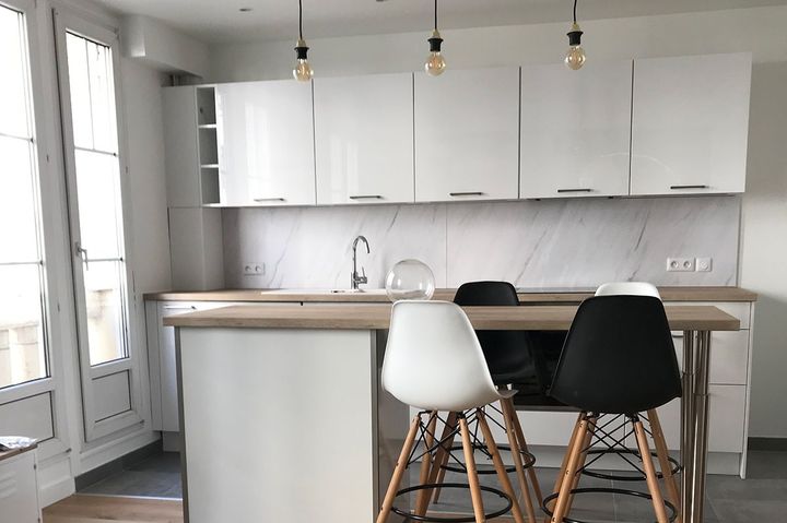 Une cuisine avec des meubles blancs et un îlot central