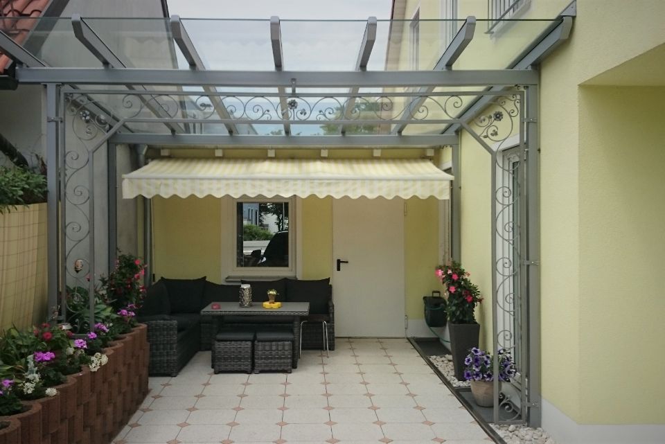 Alt Terrasse an einem gelben Haus mit Glasüberdachung