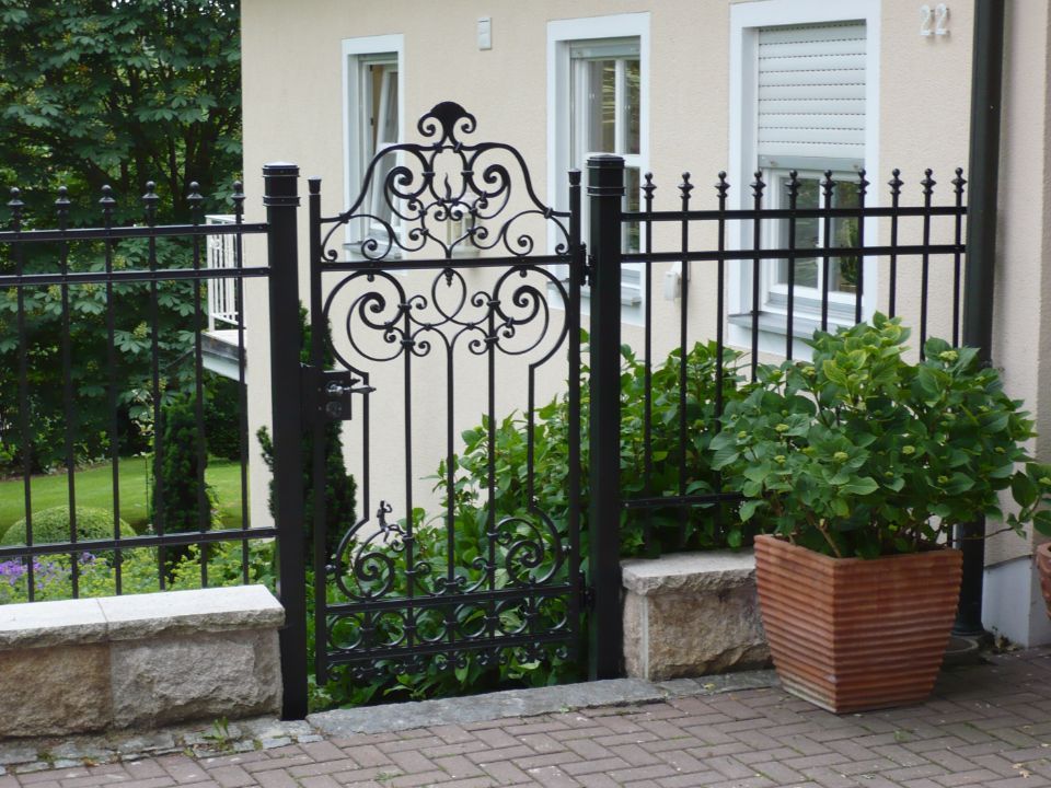 Gartenzaun mit Metallstäben und verschnörkeltem Zierelement