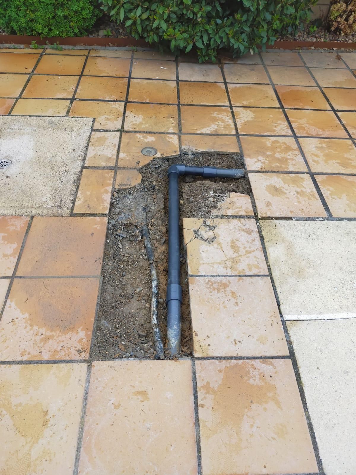 Una tubería sobresale de un agujero en el suelo sobre un piso de baldosas.