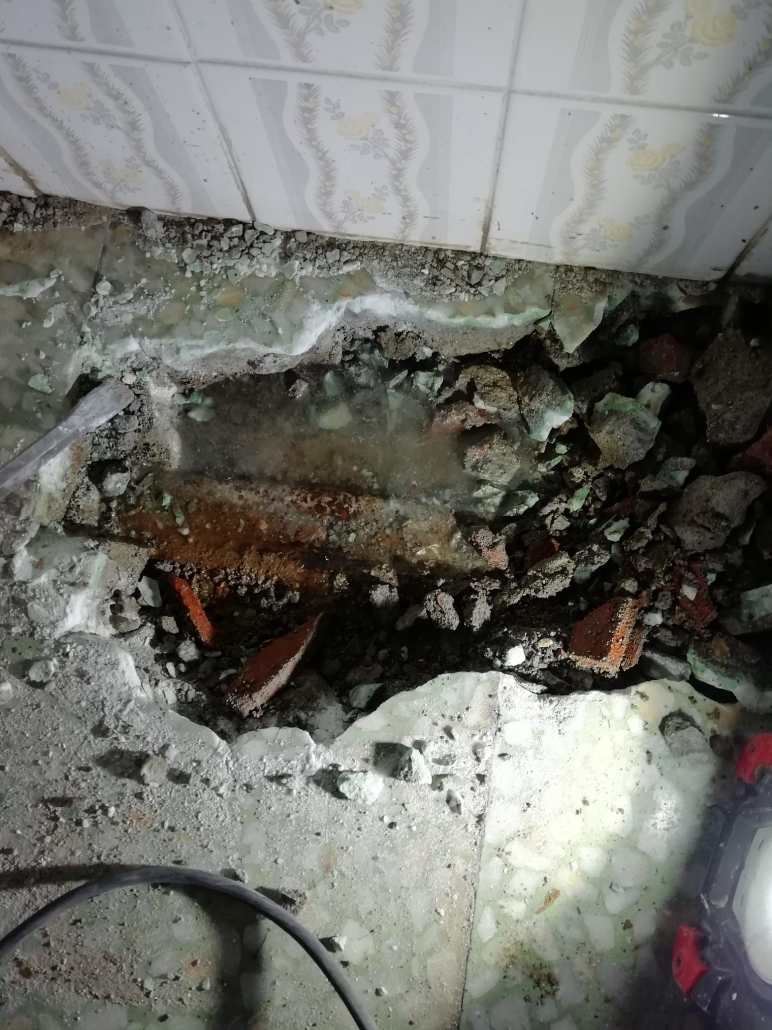 Un agujero en el suelo de un edificio del que sale agua.