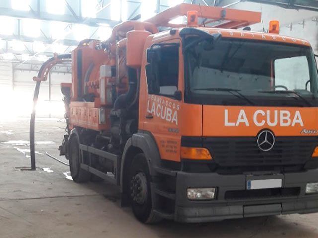 Un camión naranja de La Cuba está estacionado en un almacén.