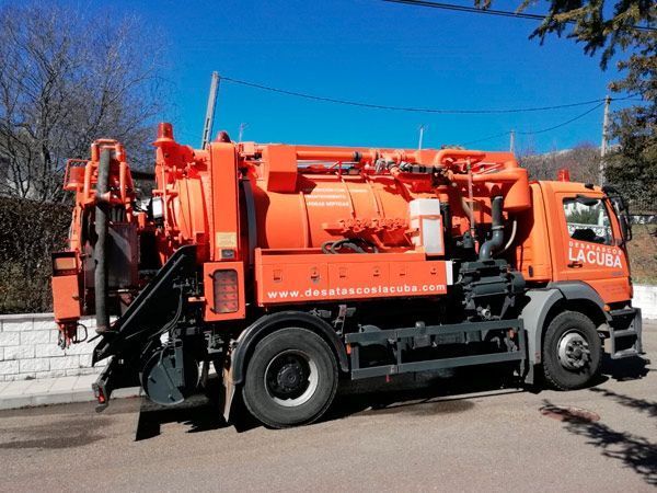 Un camión de vacío naranja está estacionado al costado de la carretera.