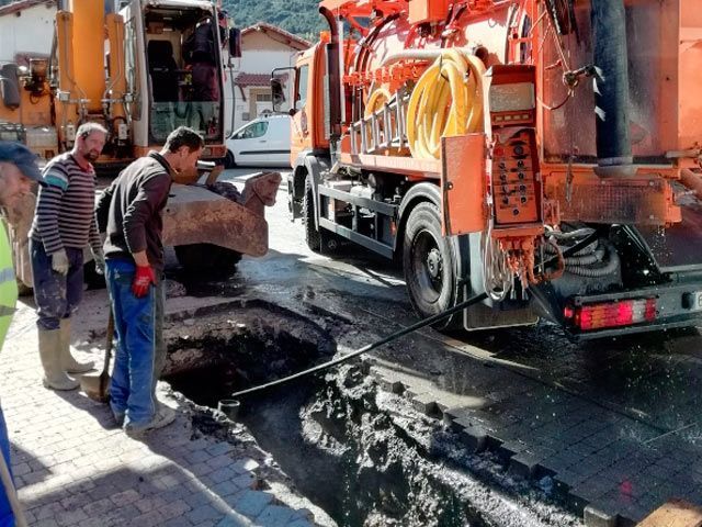 Un grupo de hombres está trabajando en un agujero en el suelo al lado de un camión.