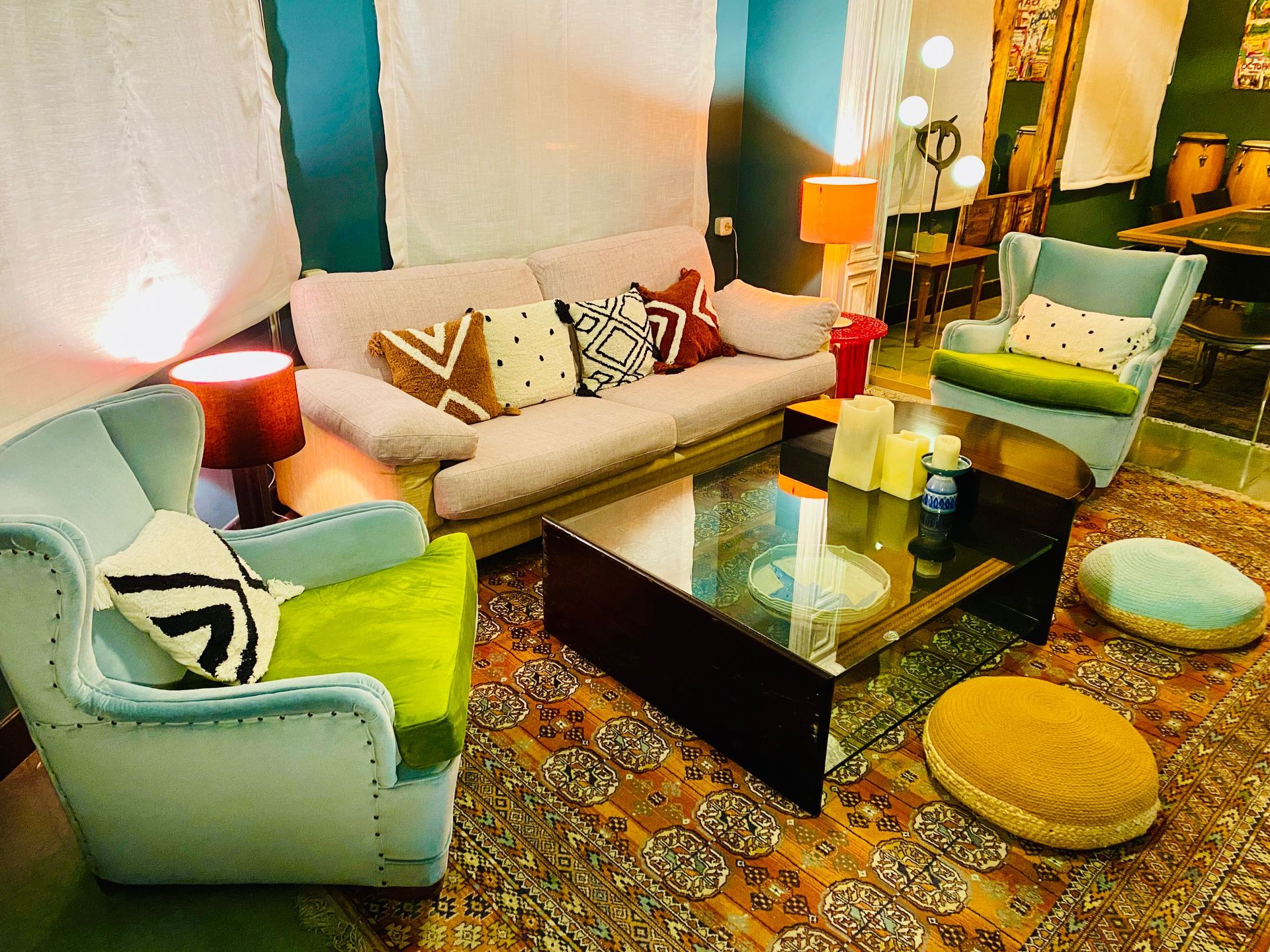 Interior con chaise longue roja, escalera, estantería y paredes color turquesa bajo iluminación cálida.