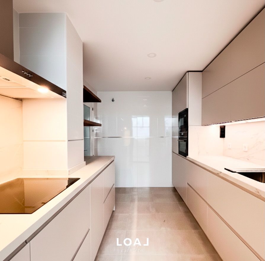 Cocina moderna y minimalista con armarios beige, salpicadero de azulejos blancos y electrodomésticos empotrados
