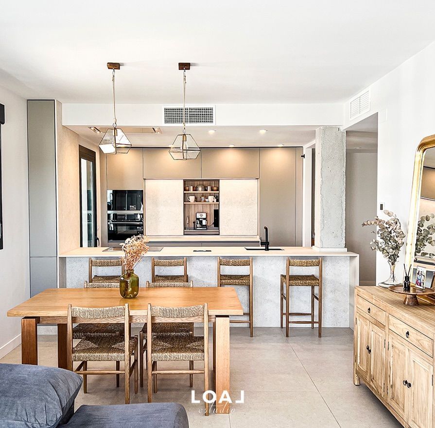 Comedor moderno y luminoso, con mesa de madera, sillas de mimbre y cocina abierta al fondo
