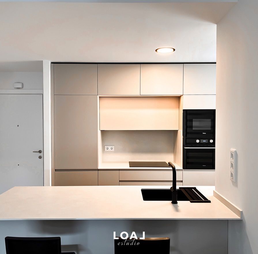 Cocina moderna y minimalista con isla blanca, fregadero negro y electrodomésticos integrados