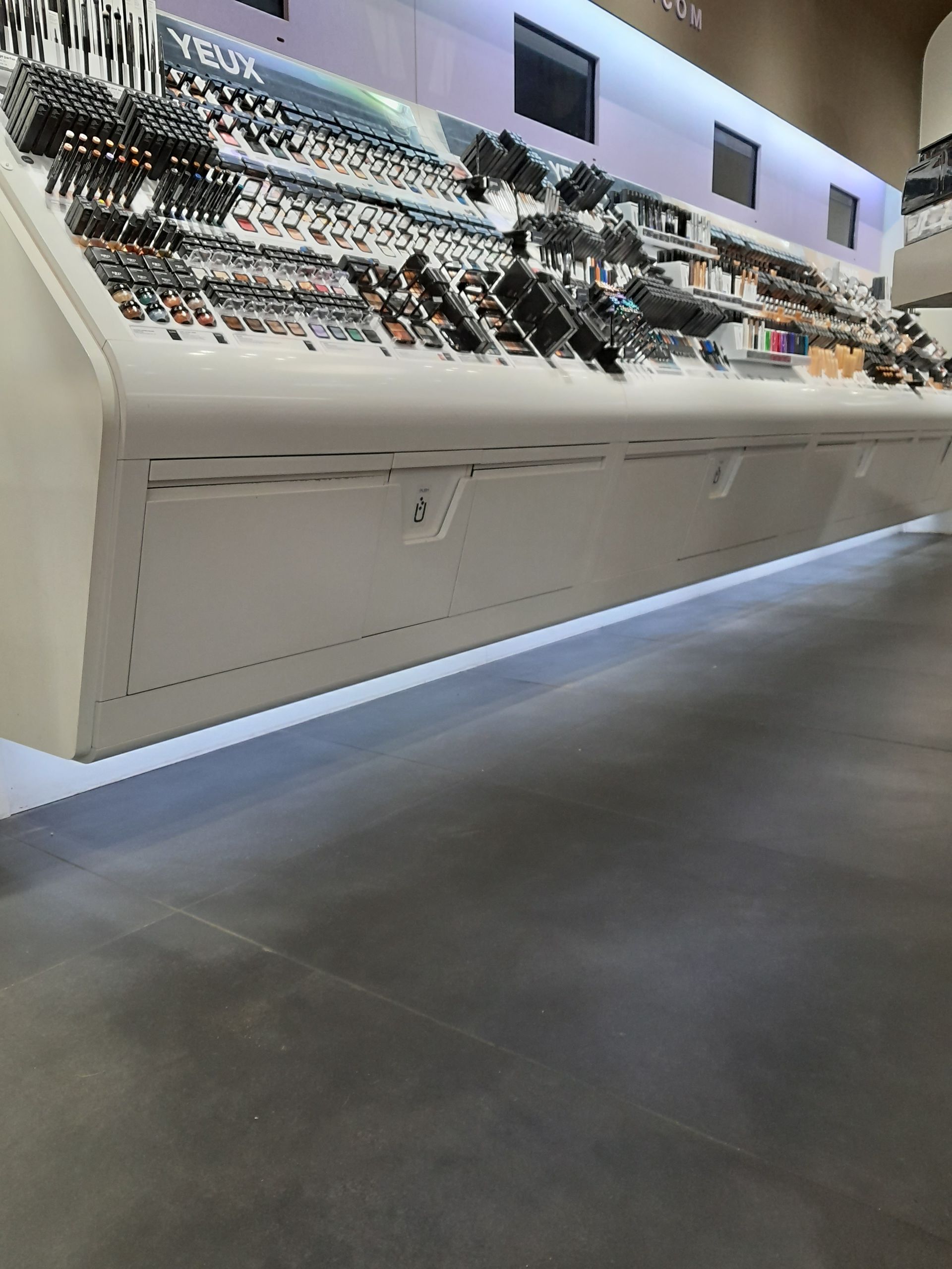 Vitrine moderne présentant des rangées de produits sous une lumière vive à l'intérieur d'un magasin.