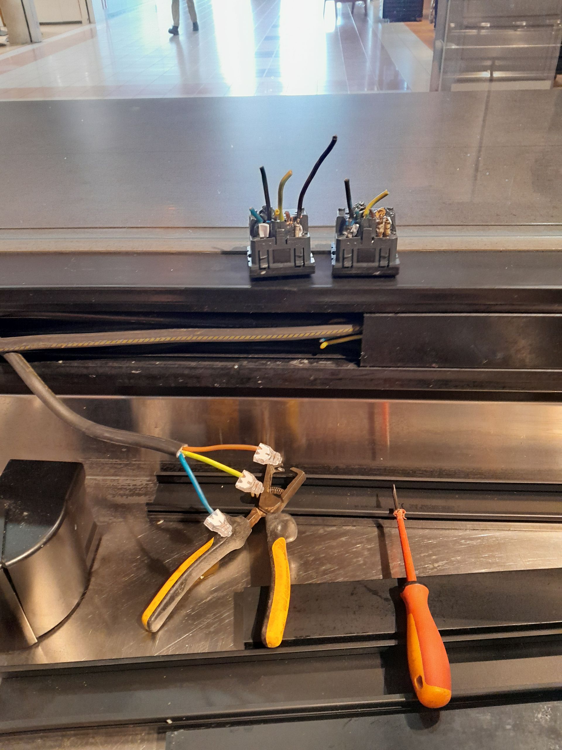 Pinces, tournevis et connecteurs de fils sur une surface métallique.