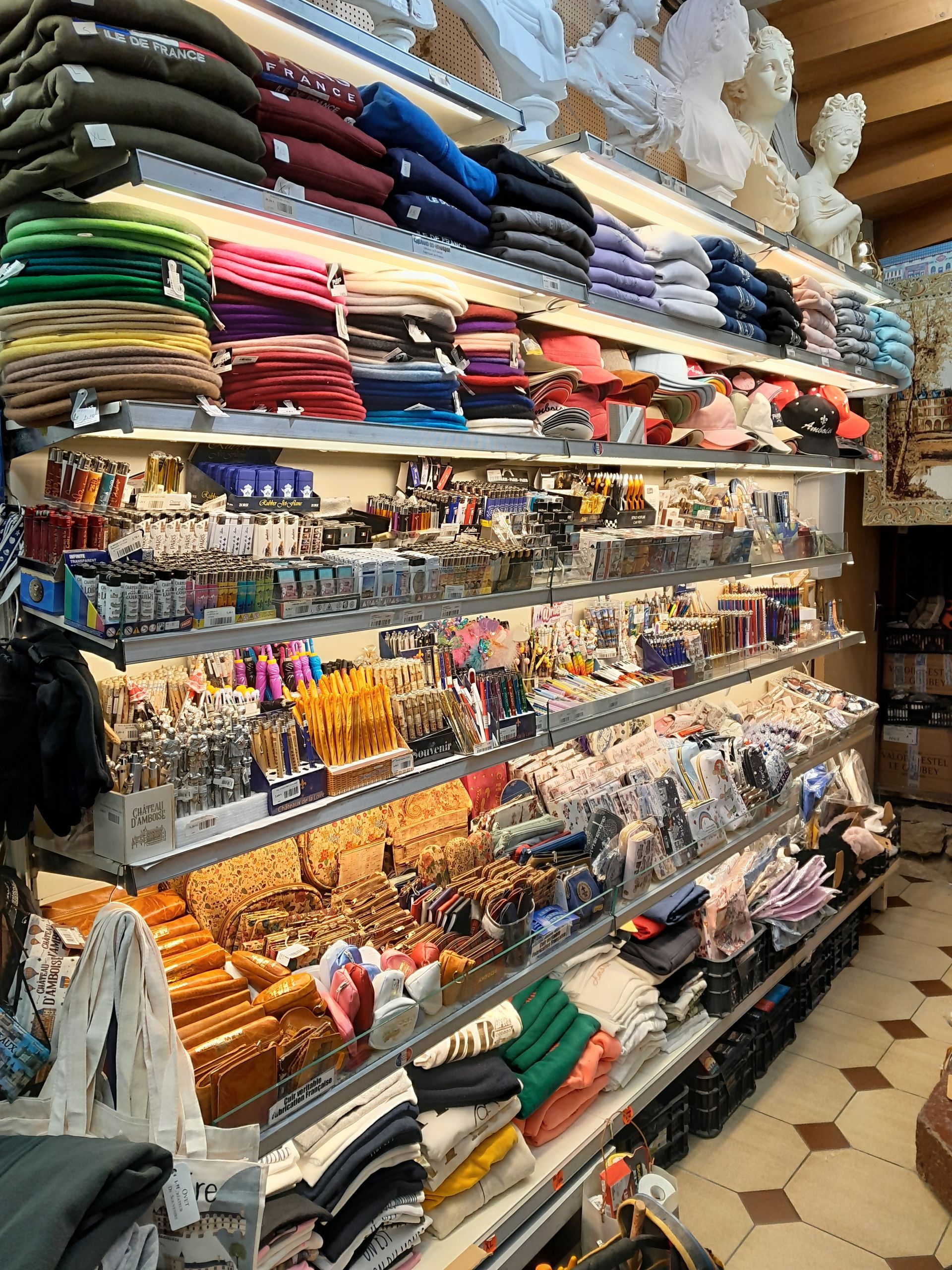 Des étagères remplies de textiles pliés et de souvenirs dans une allée de magasin.