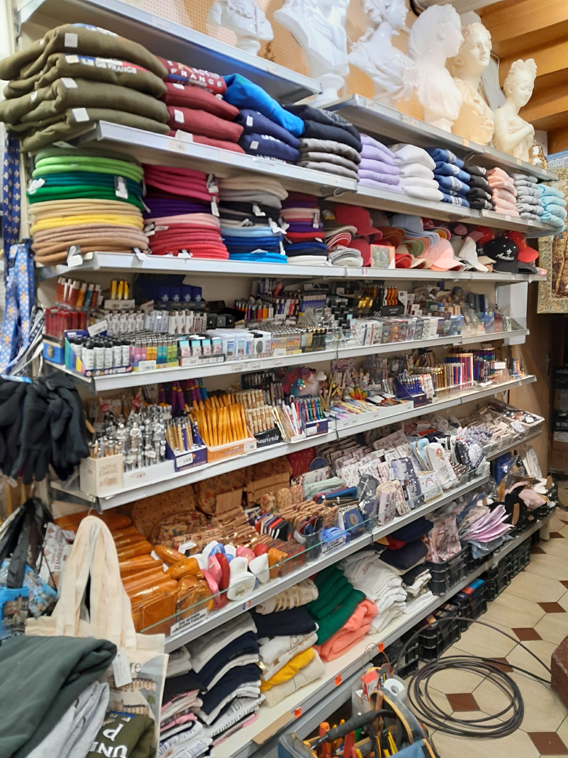 Des étagères remplies de tissus pliés, de laine et de matériel de loisirs créatifs dans une allée de magasin.