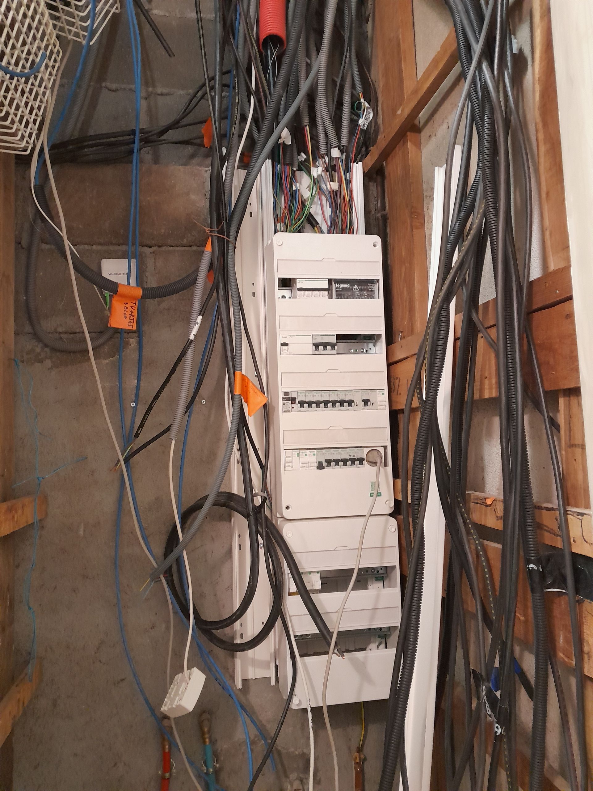 Armoire électrique avec des câbles et un panneau réseau blanc fixé au mur.