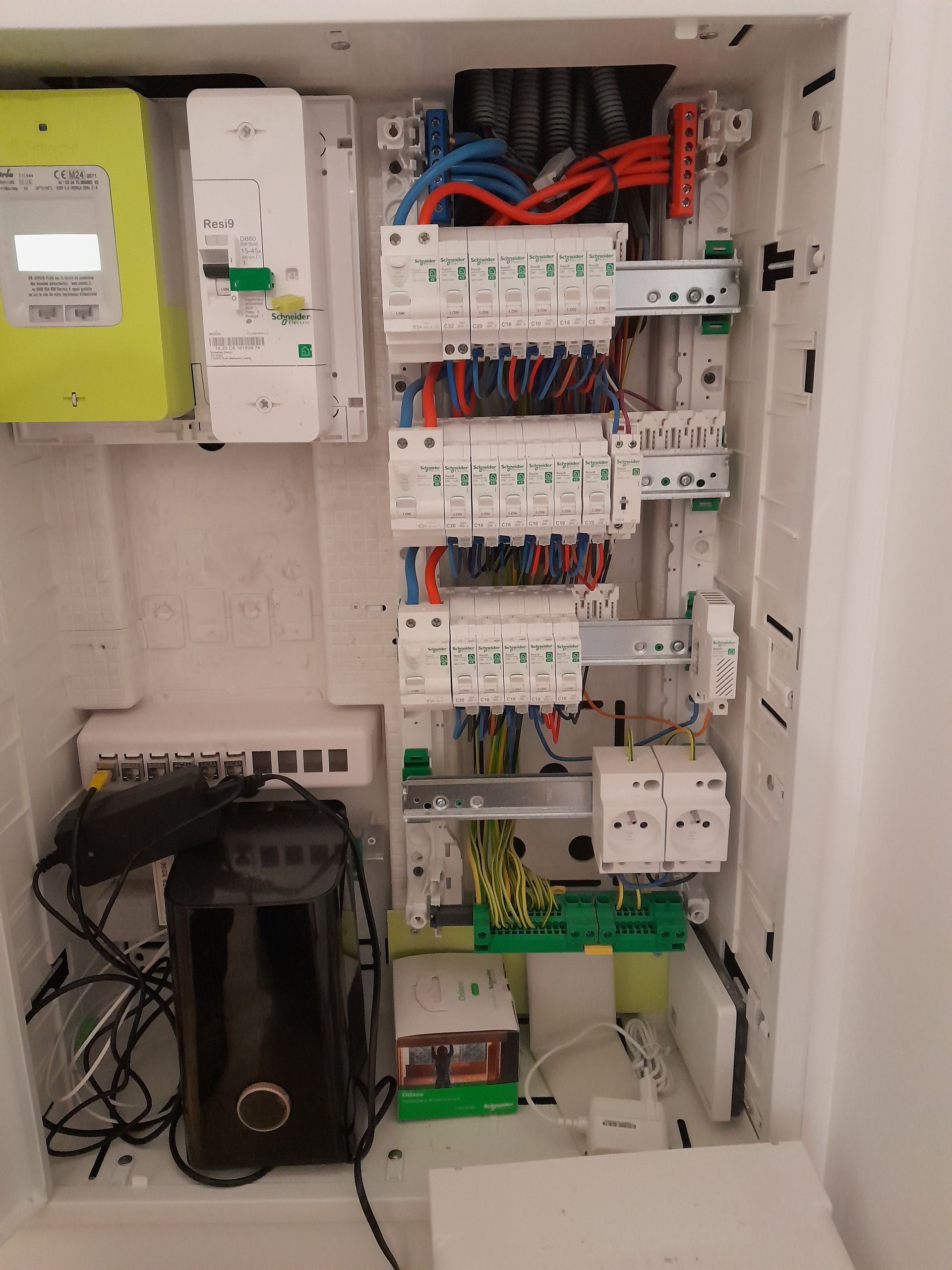 Panneau de commande électrique ouvert avec câblage, disjoncteurs et appareils montés à l'intérieur d'une armoire blanche.