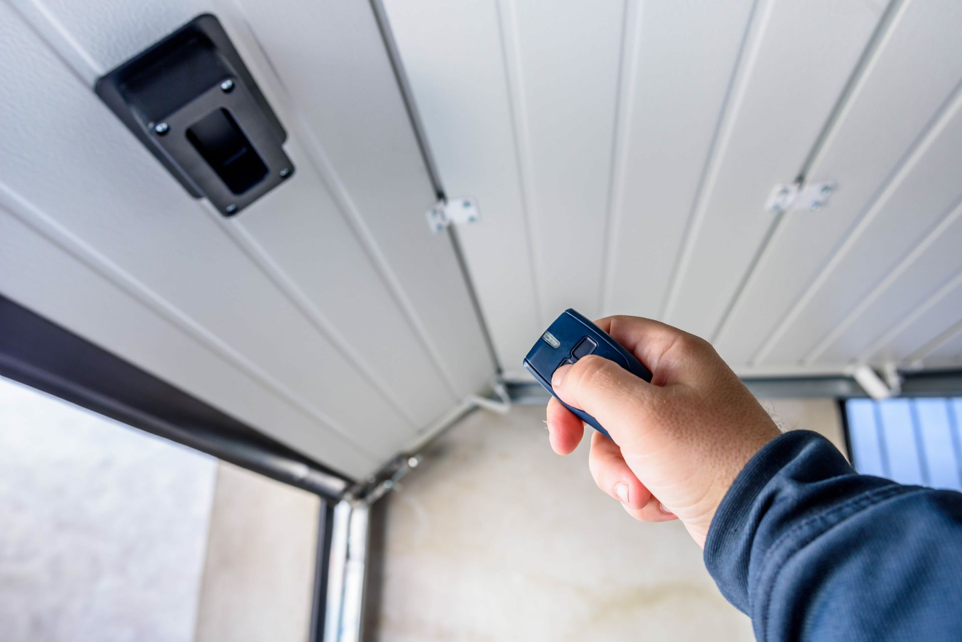 Une main tenant une télécommande pour ouvrir une porte de garage.