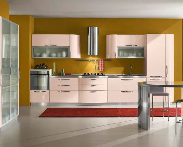 Una cocina con gabinetes rosas y paredes amarillas.