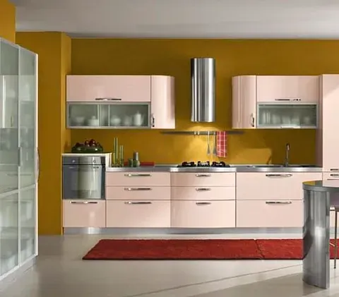 Una cocina con gabinetes rosas y paredes amarillas.