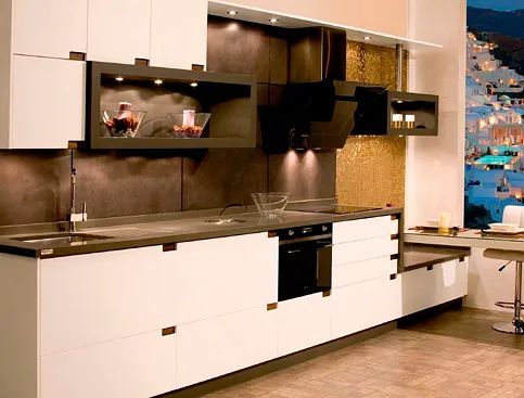 Una cocina con gabinetes blancos y electrodomésticos negros.