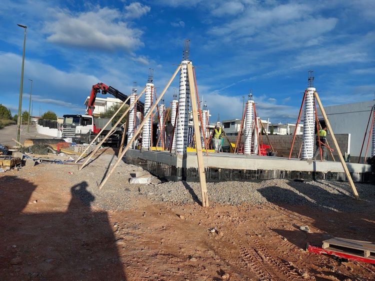 Edificio de varias plantas en construcción con estructura de madera a la vista y trabajadores en la obra.