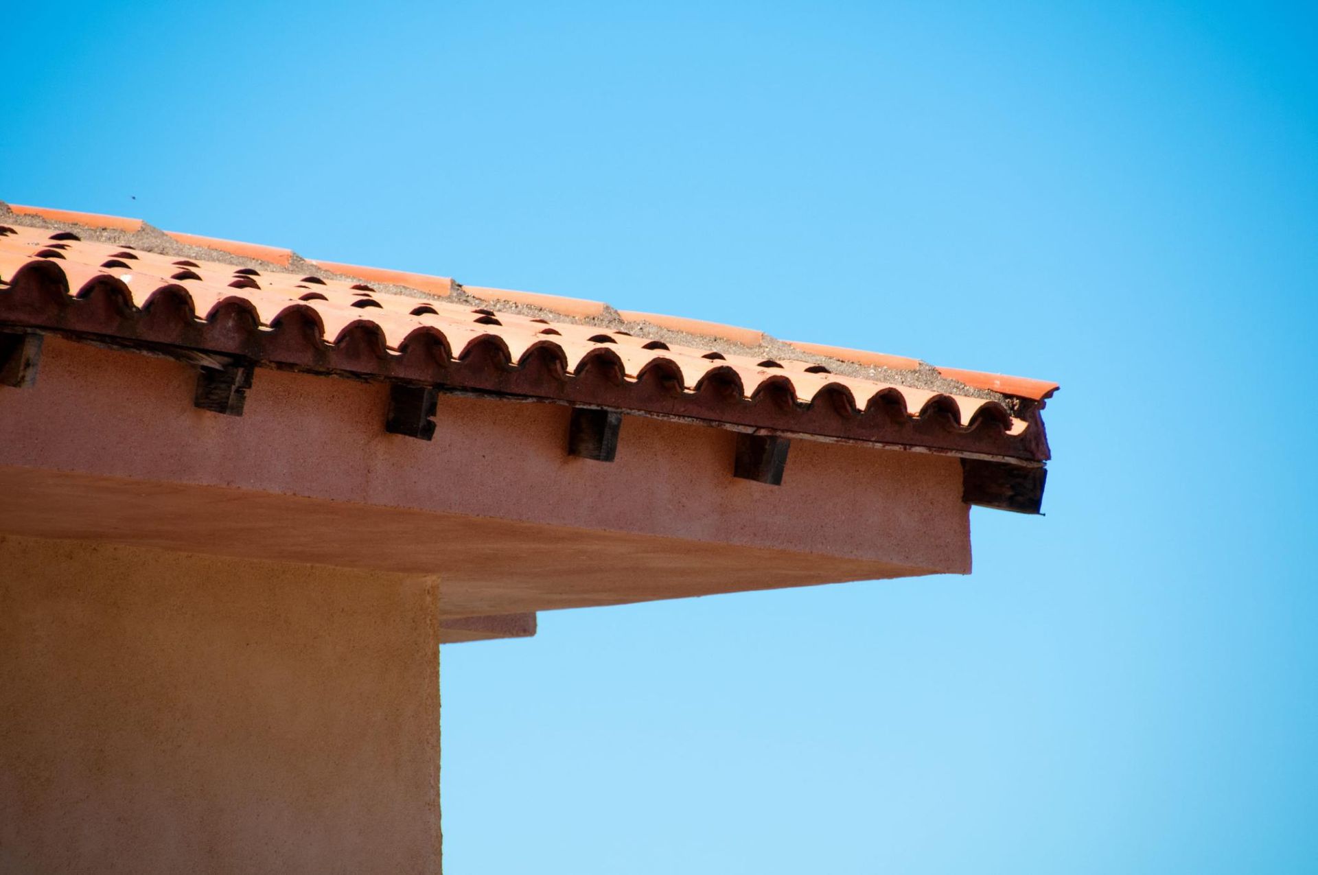 Borde de tejado de terracota con fondo de cielo azul