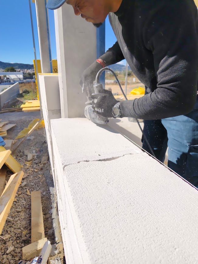 Un trabajador rocía espuma aislante blanca sobre el alféizar de una ventana en una obra de construcción.