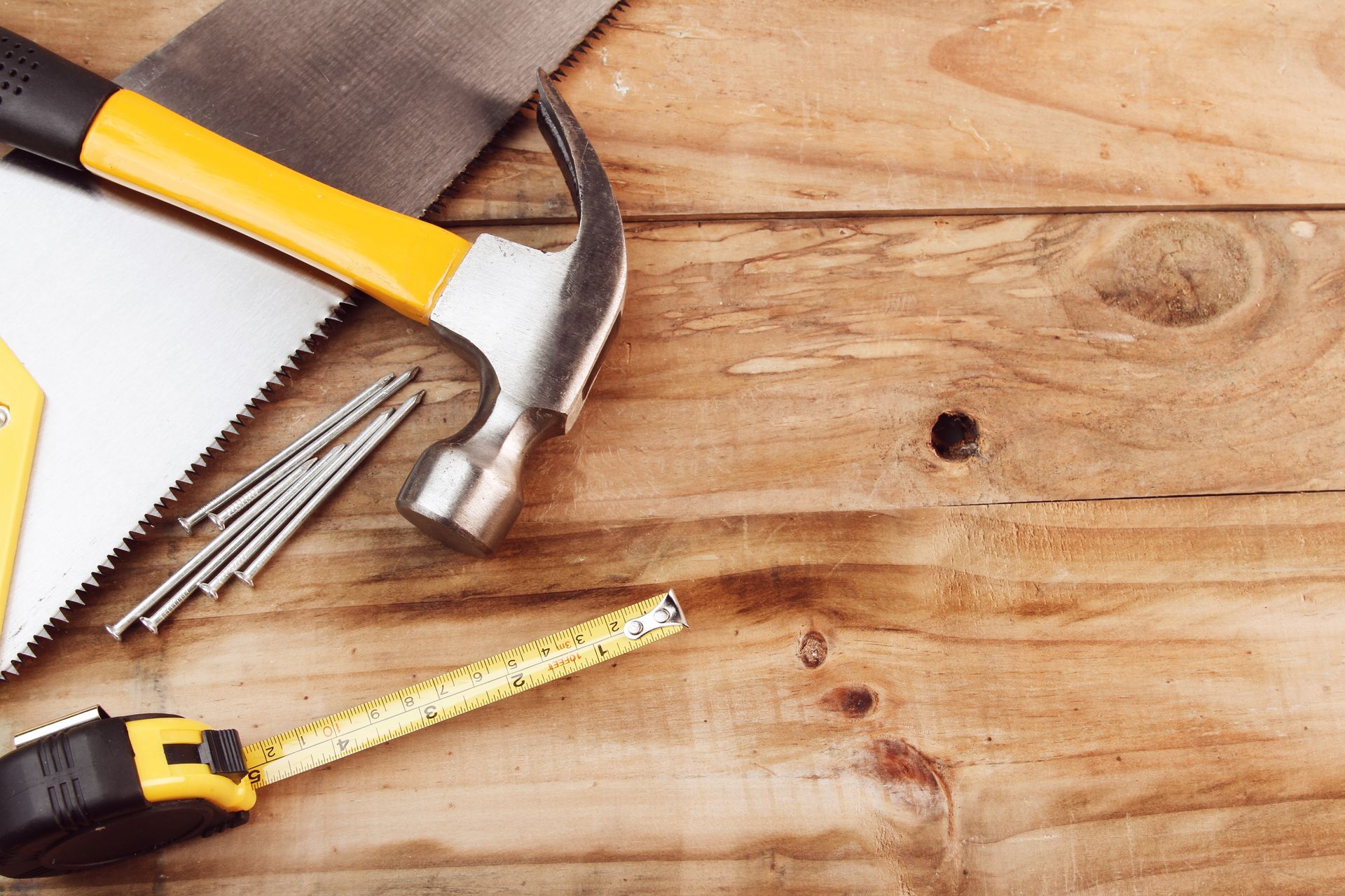 Outils sur bois : scie, marteau, clous, mètre ruban. Touches jaunes et noires, ambiance rustique.