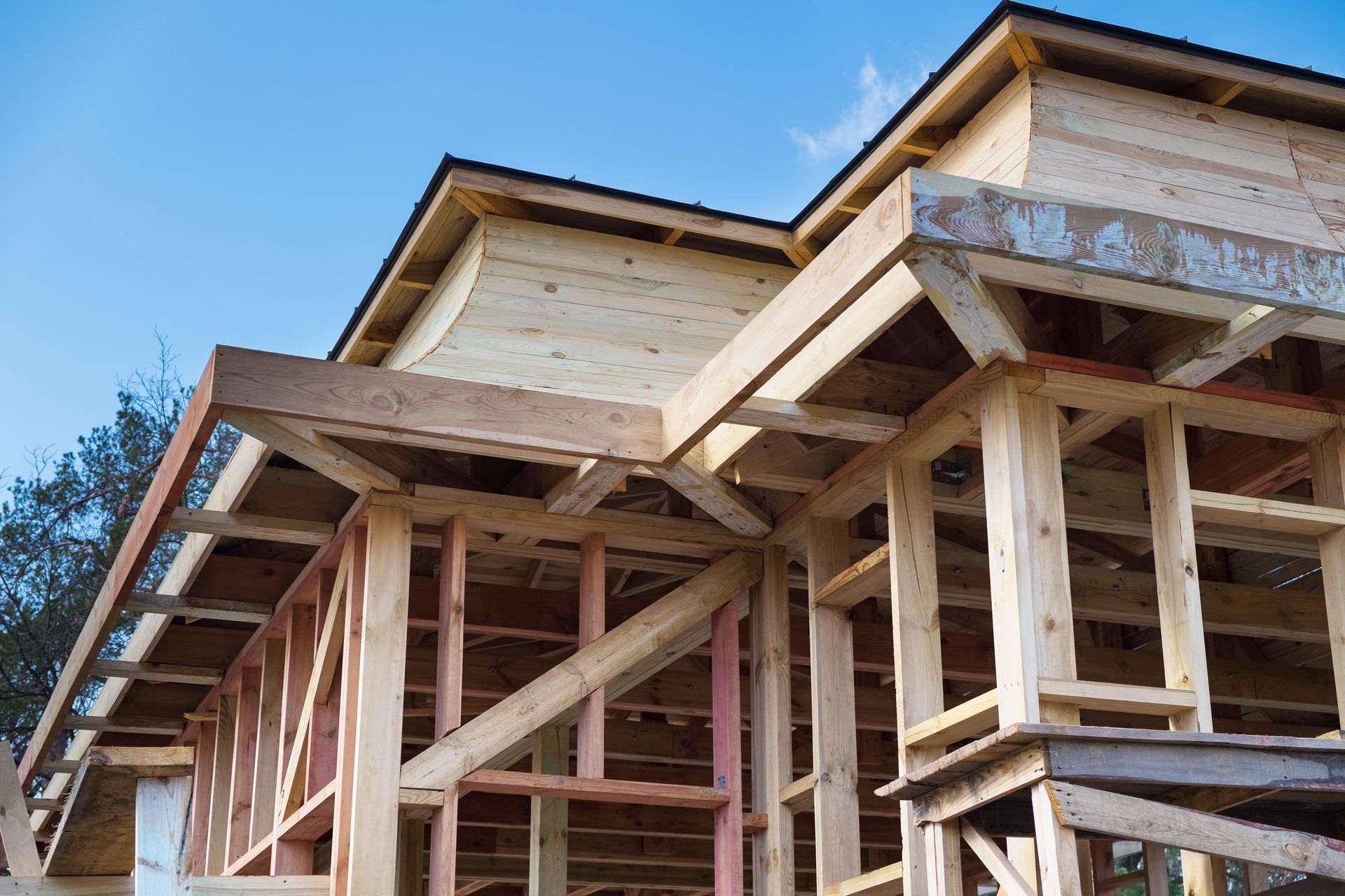 Ossature en bois d'une maison en construction contre un ciel bleu.