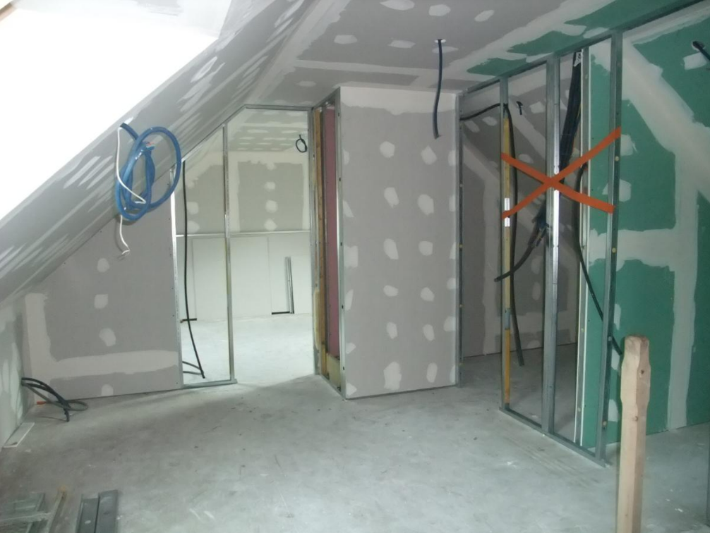 Intérieur en construction ; cloisons sèches sur ossature métallique. Câbles et conduits visibles.