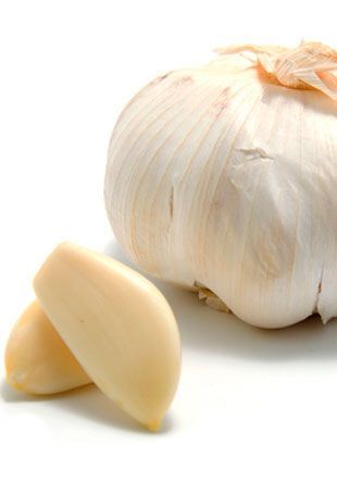 Bulbo de ajo con dos dientes pelados, fondo blanco.